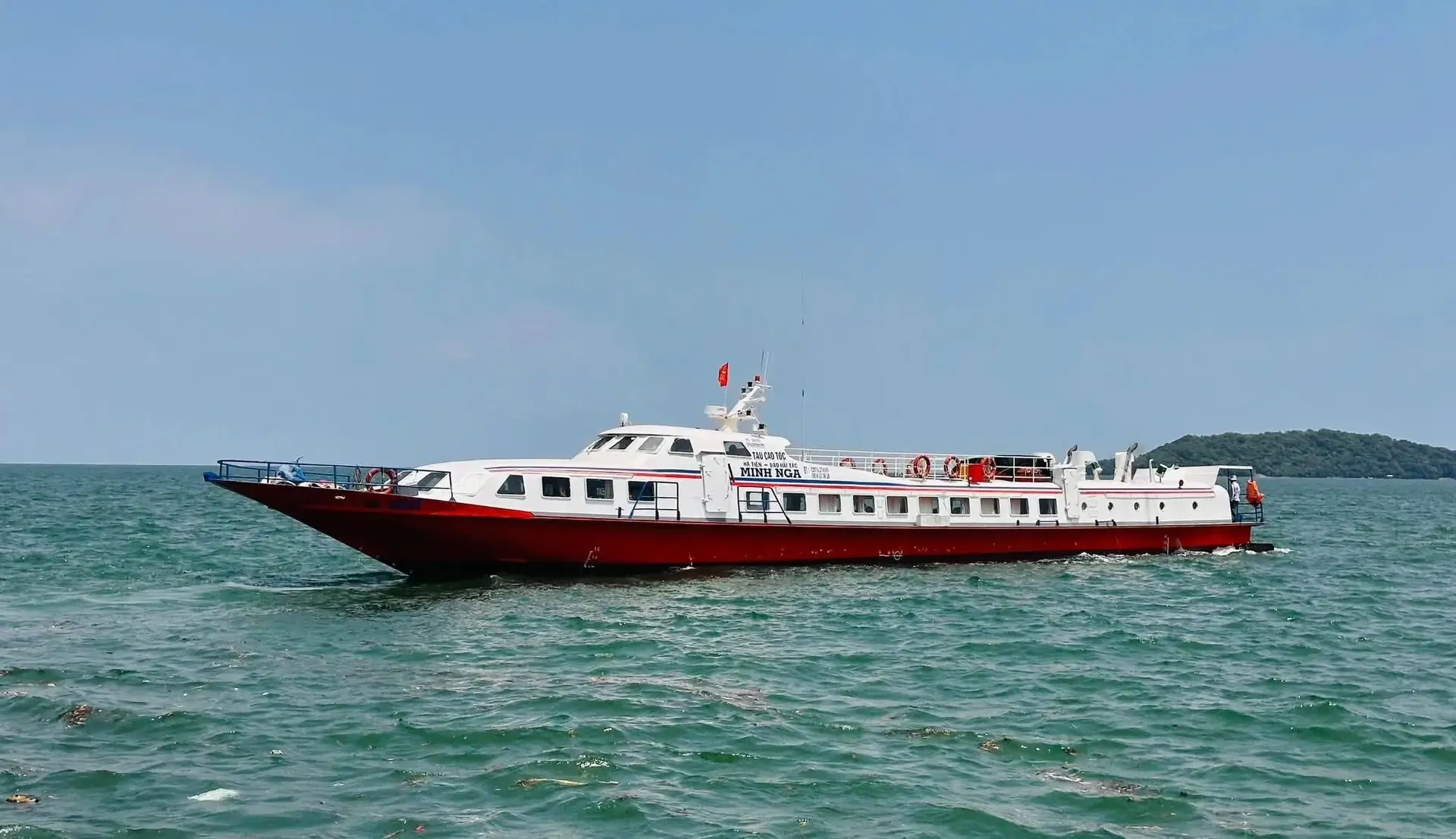 Tàu cao tốc Minh Nga thân đỏ, cabin trắng chạy trên biển xanh, hòn đảo nhỏ phía xa